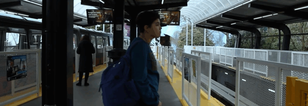 still from a film of a student standing at a monorail station