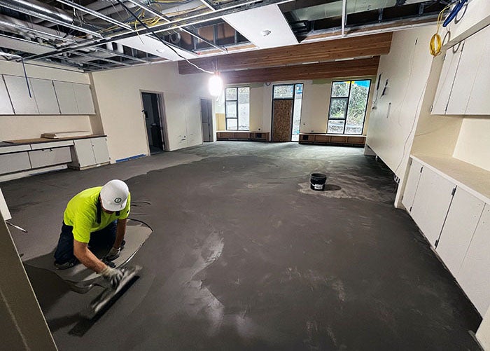 a worker is spreading a soft gray/brown material on a floor
