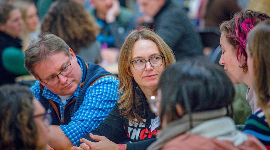Community members talking at a table at a Superintendent community meeting in the Salmon Bay Cafeteria