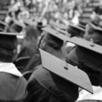 graduates in cap and gown sitting at graduation ceremony