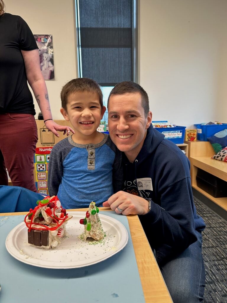Picture of a parent volunteer and student building gingerbread houses