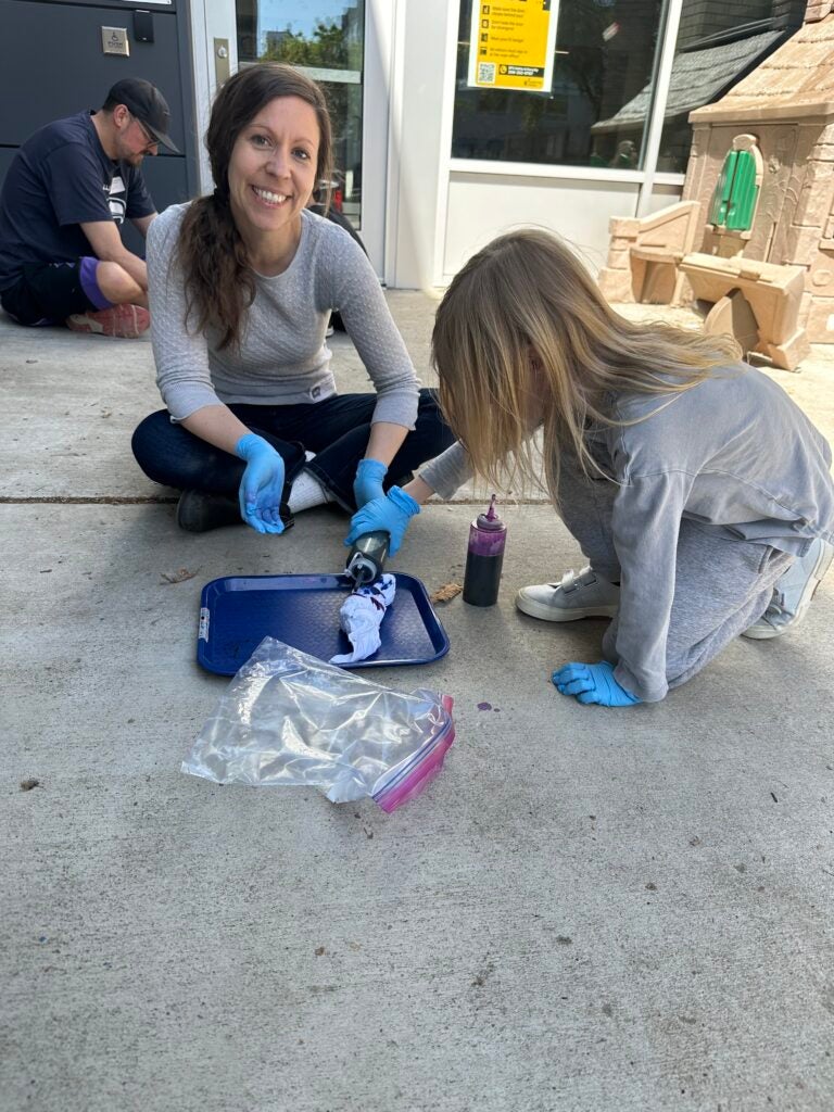 A parent volunteer tye dying with a student