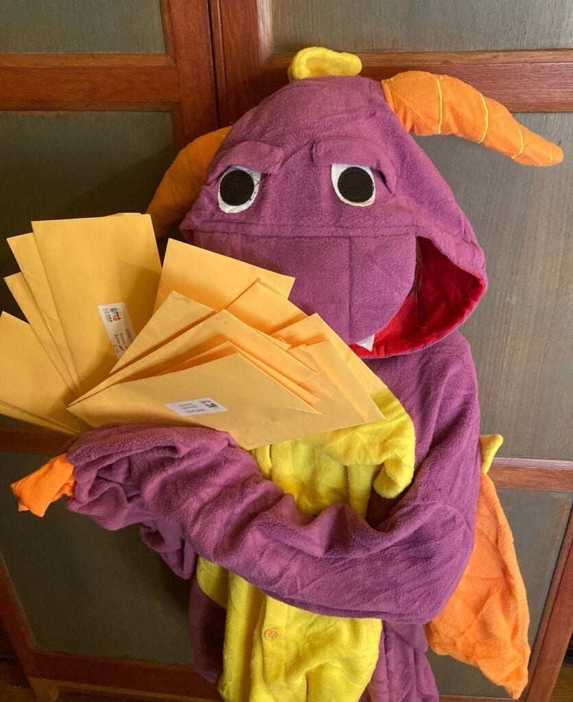 Dragon Costume Holding handfuls of envelopes.