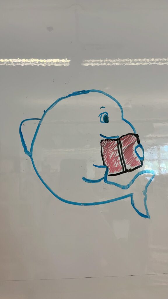 student drawn image of a dolphin holding a book