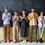Students standing in front of chalkboard all on cell phones