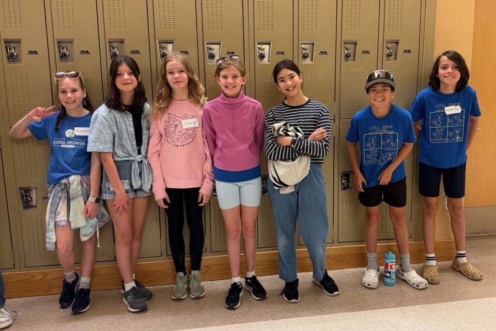 a group of students standing in a row in school by lockers