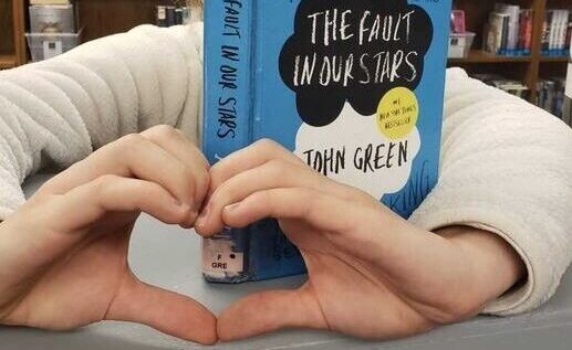 TuesD with a book and making a heart with her hands