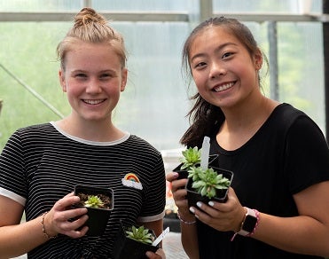 Two students hold plants at Skills Center course