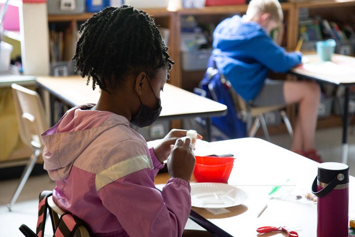 A student sites at a desk wearing a mask in a classroom