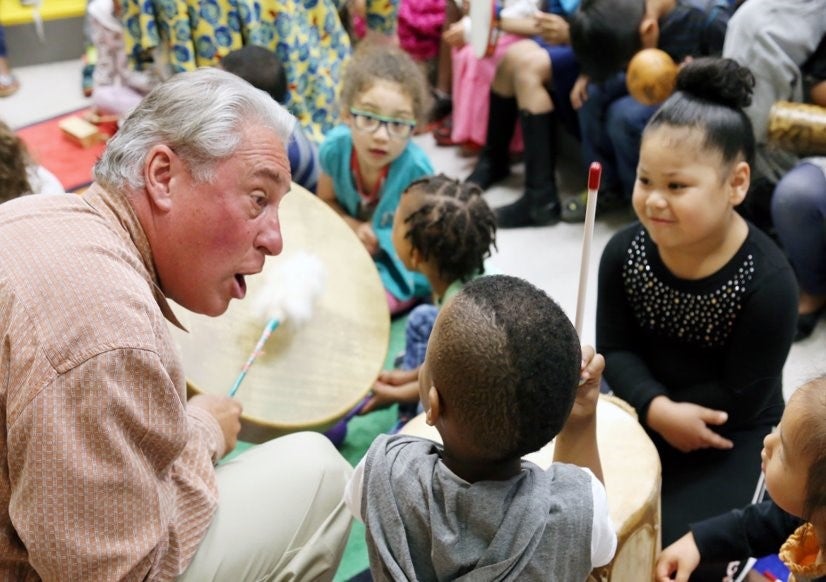 Teaching artist drumming with 3 elementary children