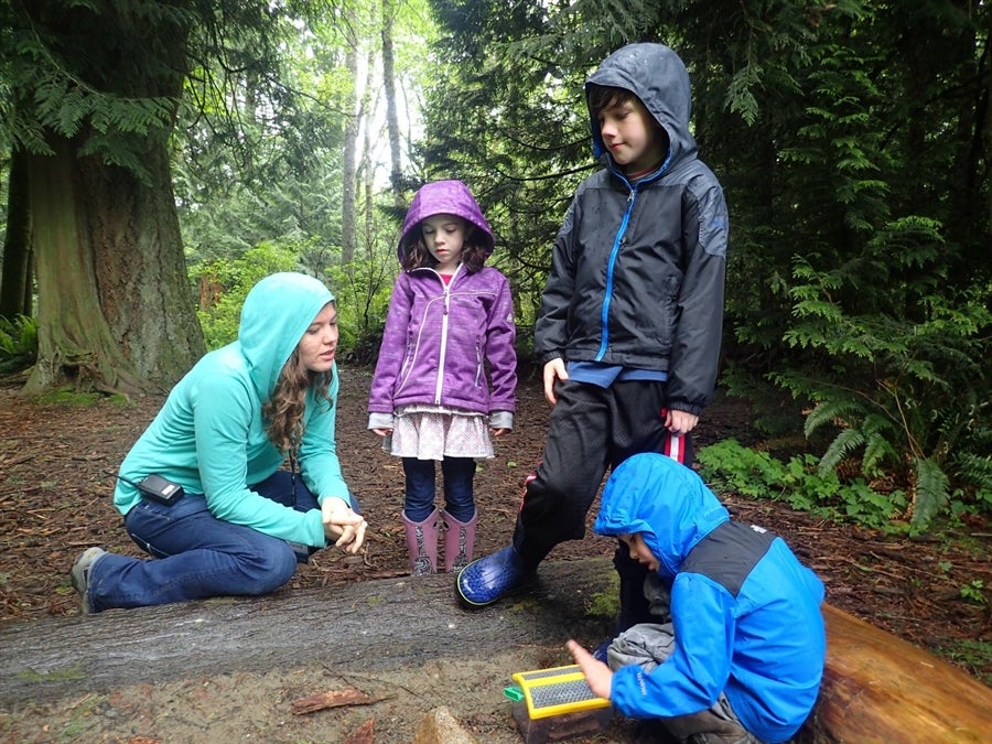 Photo of teacher and small children in woods