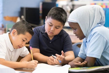 Three students work together in a classroom