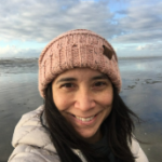 Woman in a pink winter beanie on the ocean shore