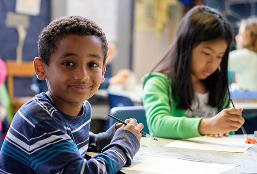 A young student looks at the camera and smiles for a photo