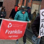 SPS staff march with a banner in a rally. Banner text says 