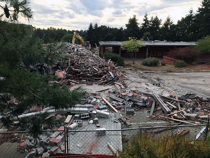 a large pile of debris including concrete blocks and wood in front of a partially demolished building