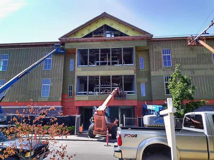 front of three story building with a peaked roof under construction
