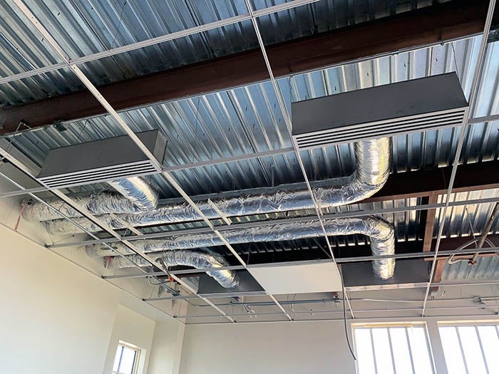 a ceiling with metal tubing and air handling vents