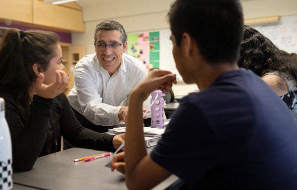 A teacher talks with high school age students in a classroom