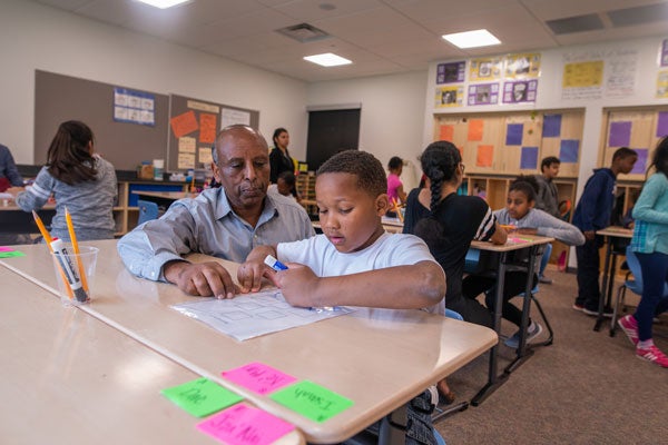 An educator and student talk in a classroom.