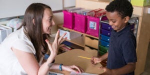 A teacher talks with a young student in a classroom