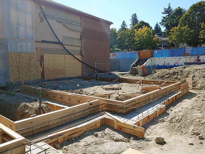 a building with the siding removed and wood forms for concrete stem walls