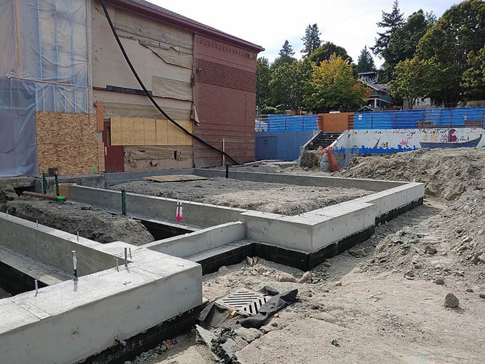 a building with the siding removed and low concrete rectangle walls