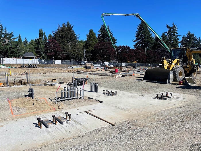 concrete pads with pipes sticking out and a construction vehicle