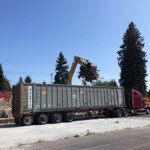 a construction dumpter is being loaded with debris using heavy equipment