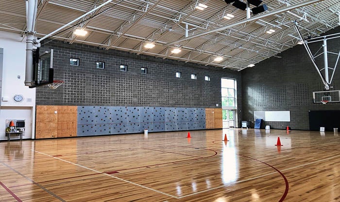 a gym with a climbing wall and basketball hoops