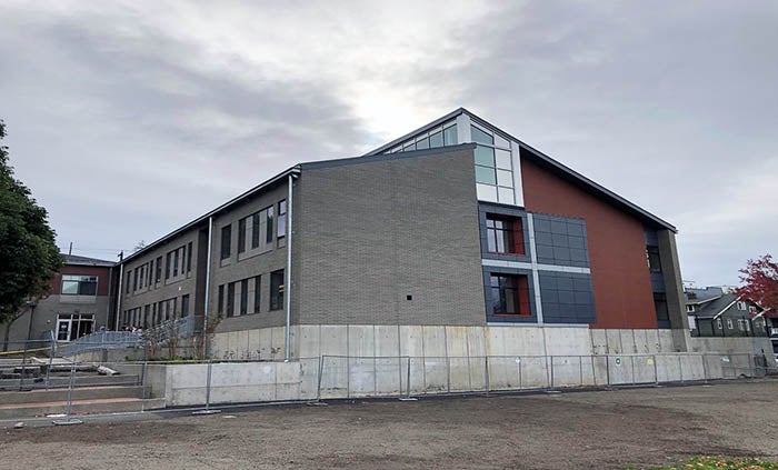 a building that is half gray brick and half red brick with a concrete wall below