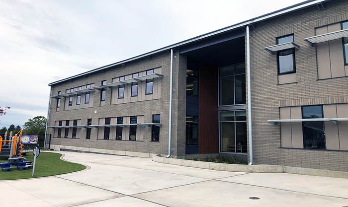 a two story gray brick building with windows