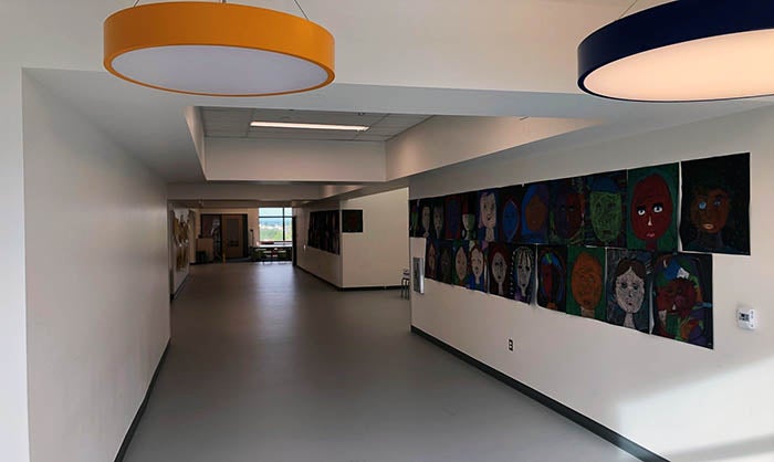 a hallway with round ceiling lights and children's artwork on the wall