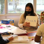 A teacher and two students work on school work in a classroom