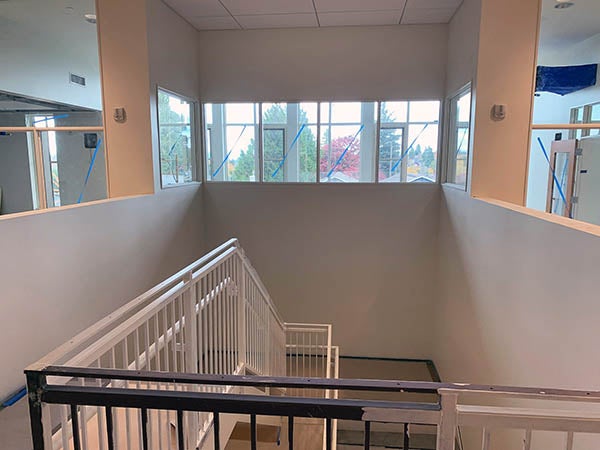 looking down a stairway from the top toward a landing where it reverses. there are windows straight ahead