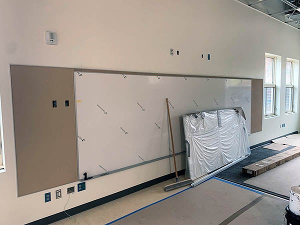 a white boared has tack board on each side and electrical outlets above and below