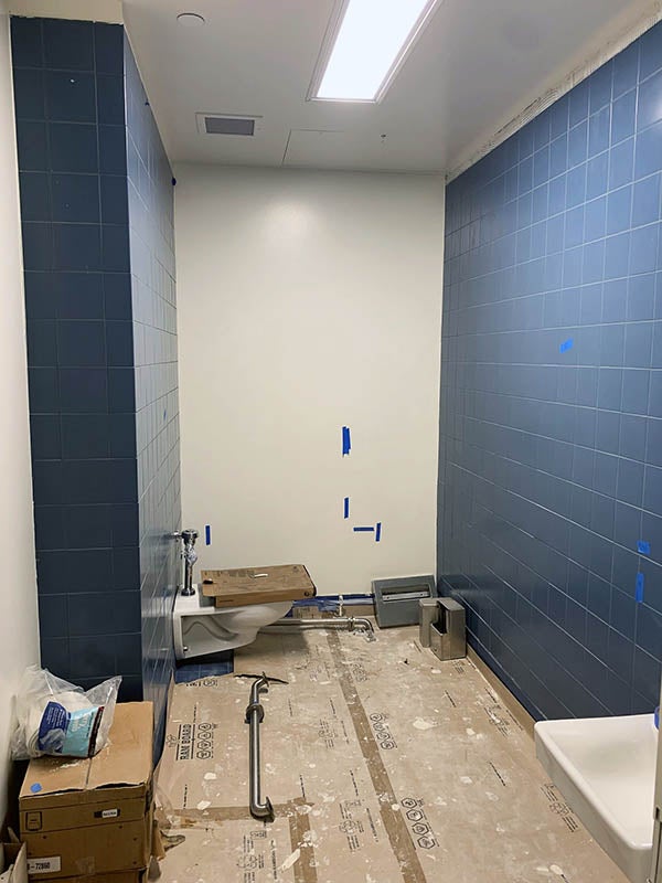 a small space with a toilet has blue tiles on two walls