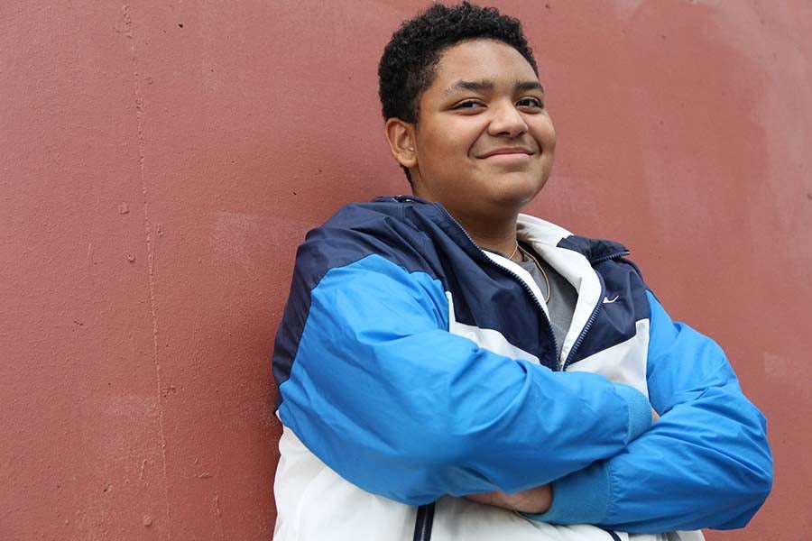 A high school student poses for a photo outside a school