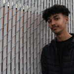Brandon Johnson stands in front of a school fence.