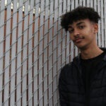 Brandon Johnson stands in front of a school fence.