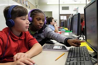Two students work together at a computer in a classroom