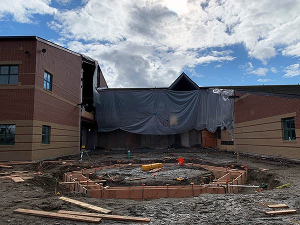 a 2 story building has tarps in front of the entry and concrete forms set in an octagon