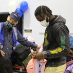 Taylor and a Seahawk assistant help students pick up coats at a school event.