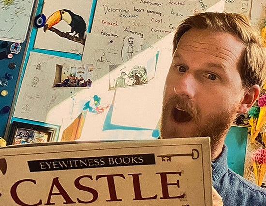 Thomas Castle poses for a photo with a book with title Castle