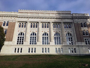 a large brick building has white columns and arched windows