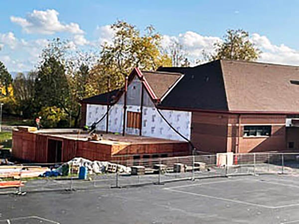 a building under construction with a one story partial building attached to an existing 2-story building