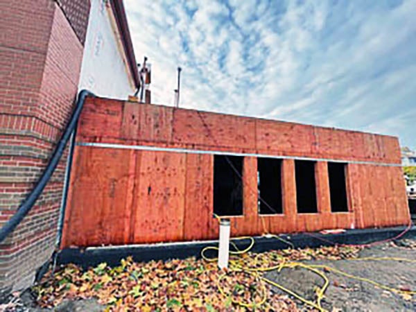 a one story building addition under construction is attached to a brick building