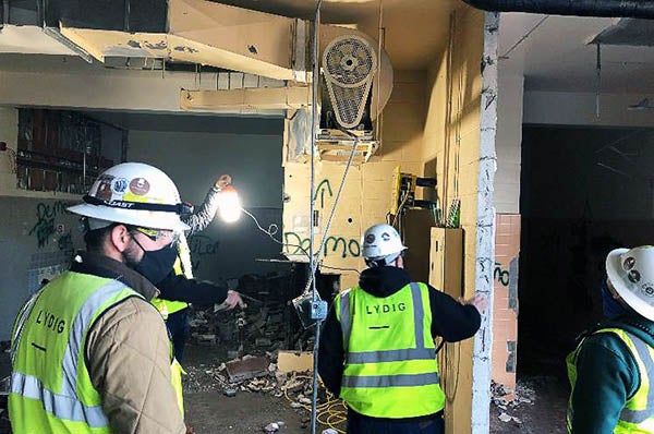 people in safety vests and hats looking at demolition