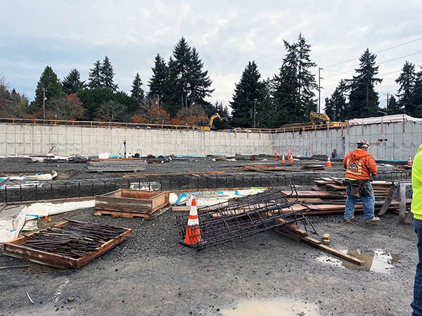 a construction project with a concrete wall across the back and concrete forms and gravel