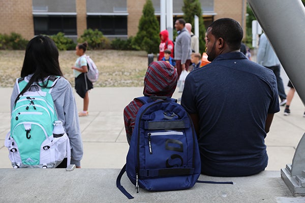 An adult and student sit together outside of a school.